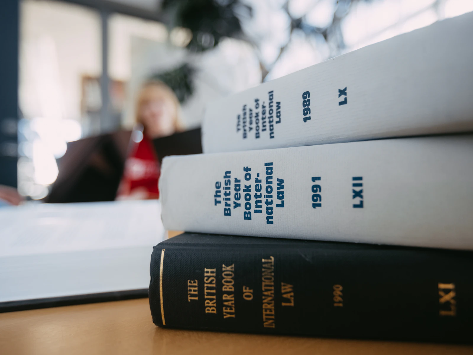 Gestapelte Rechtsbücher auf einem Schreibtisch.
